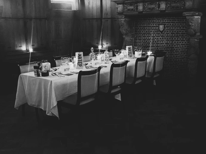 Lange, sfeervol verlichte tafel in een klassieke zaal voor een huwelijksdiner.
