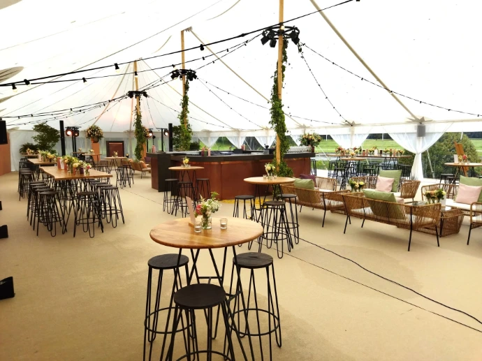 Sfeervolle stretchtent met bar, hoge bartafels en zitjes voor een evenement.