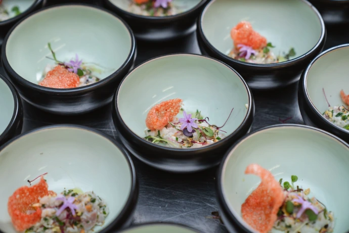 Elegante kleine voorgerechten met zalm en garnering in zwarte kommetjes.