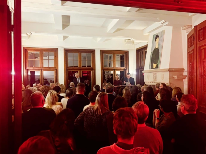 Grote evenementenzaal gevuld met publiek tijdens een plenaire sessie of presentatie.