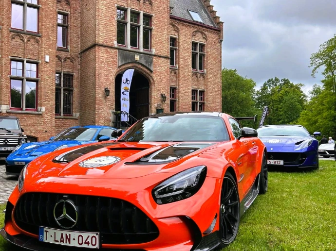 Een opvallende rode Mercedes-AMG sportwagen geparkeerd voor een historisch gebouw.