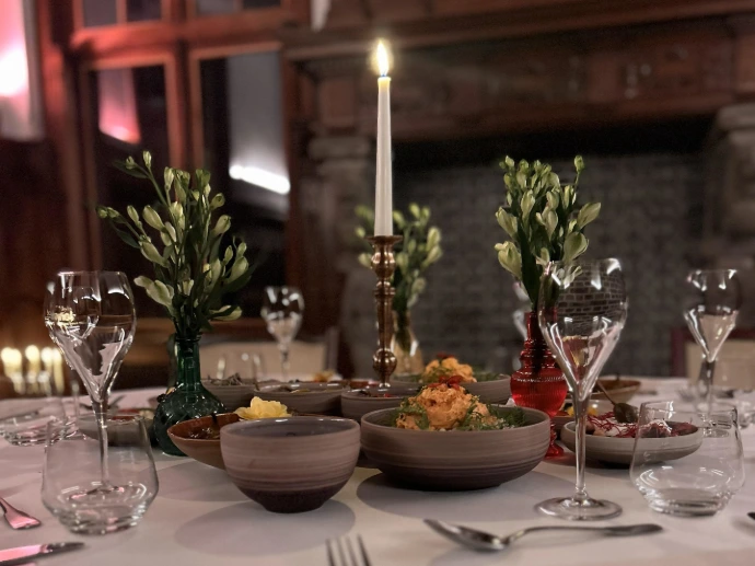 Romantisch gedekte tafel met kaarsen en bloemstukken in een rustieke ruimte.